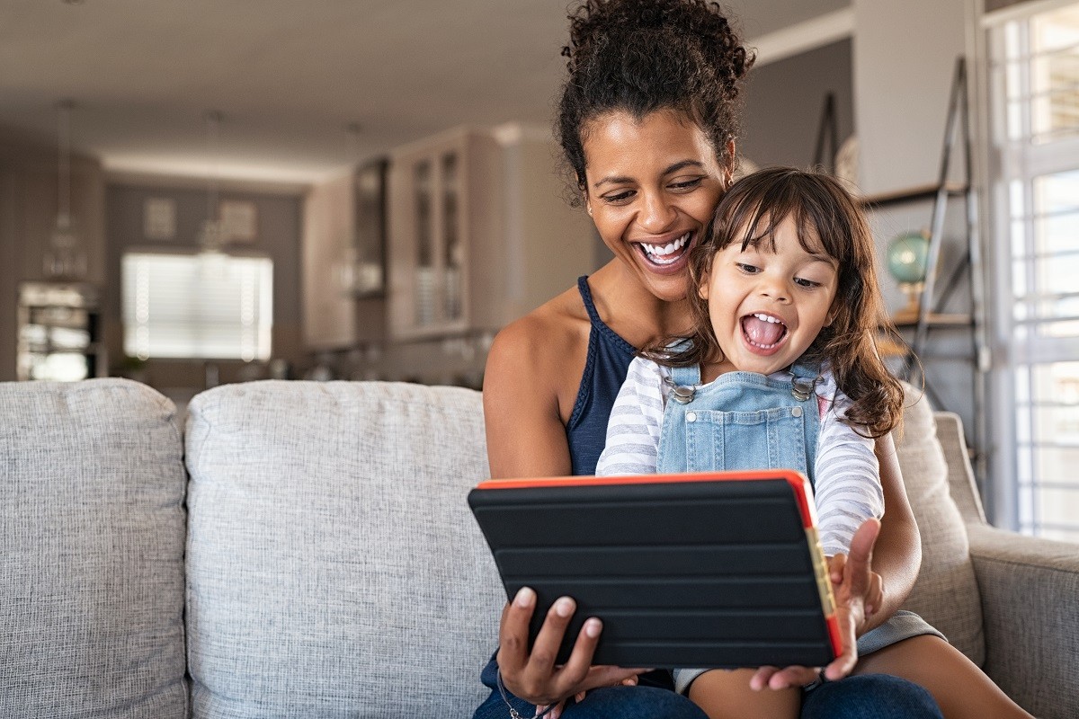 a mother and a child watching a tablet while sitting on the couch