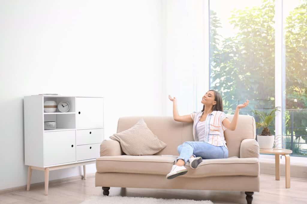 Young woman relaxing under air conditioner at home