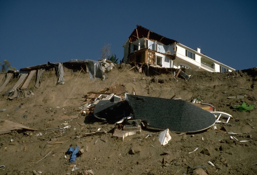 a house on a hill with parts of it tumbling off the side