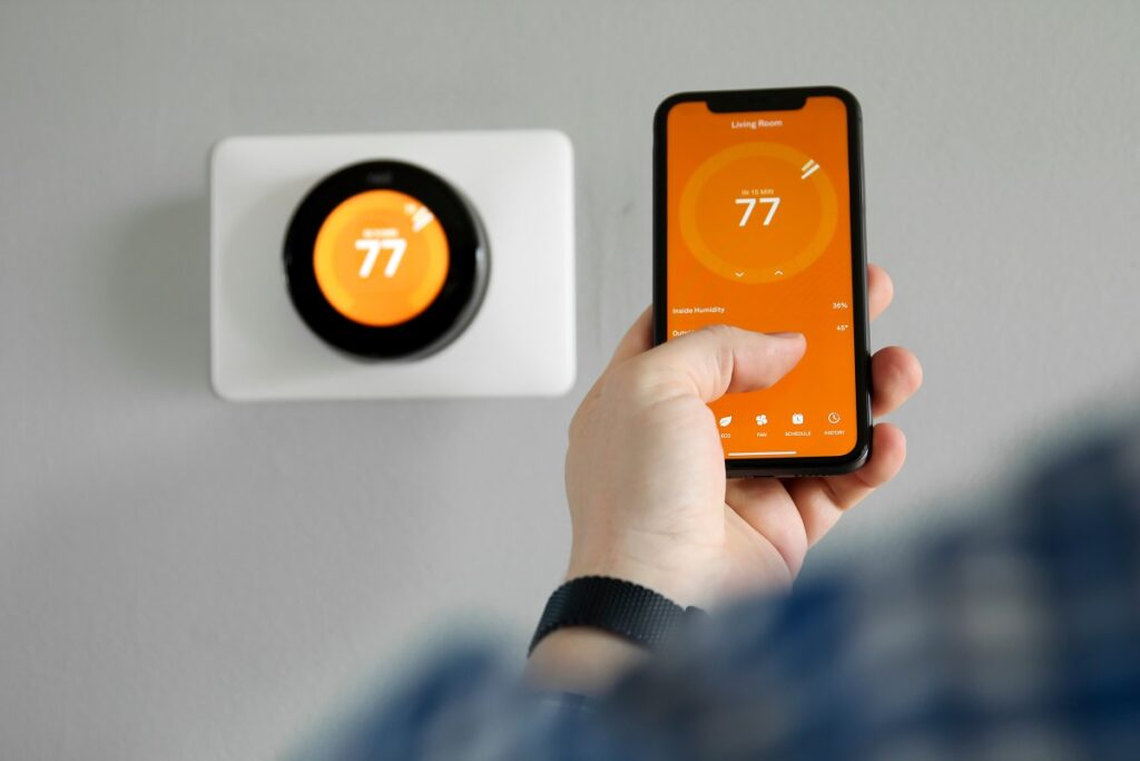 a smart thermostat being controlled by a phone - how to be energy efficient at home