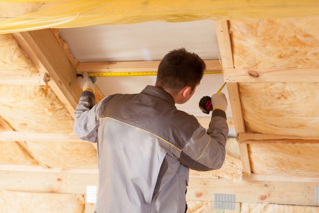 a homeowner installing new insulation in his attic - how to be energy efficient at home