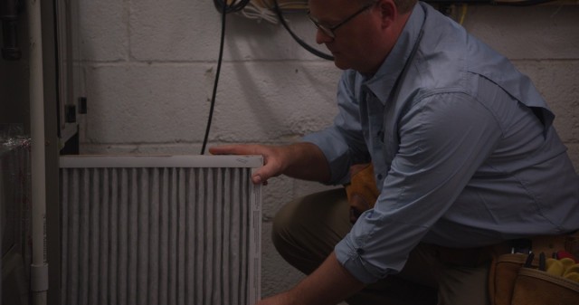 a handyman changes an air filter on an HVAC unit