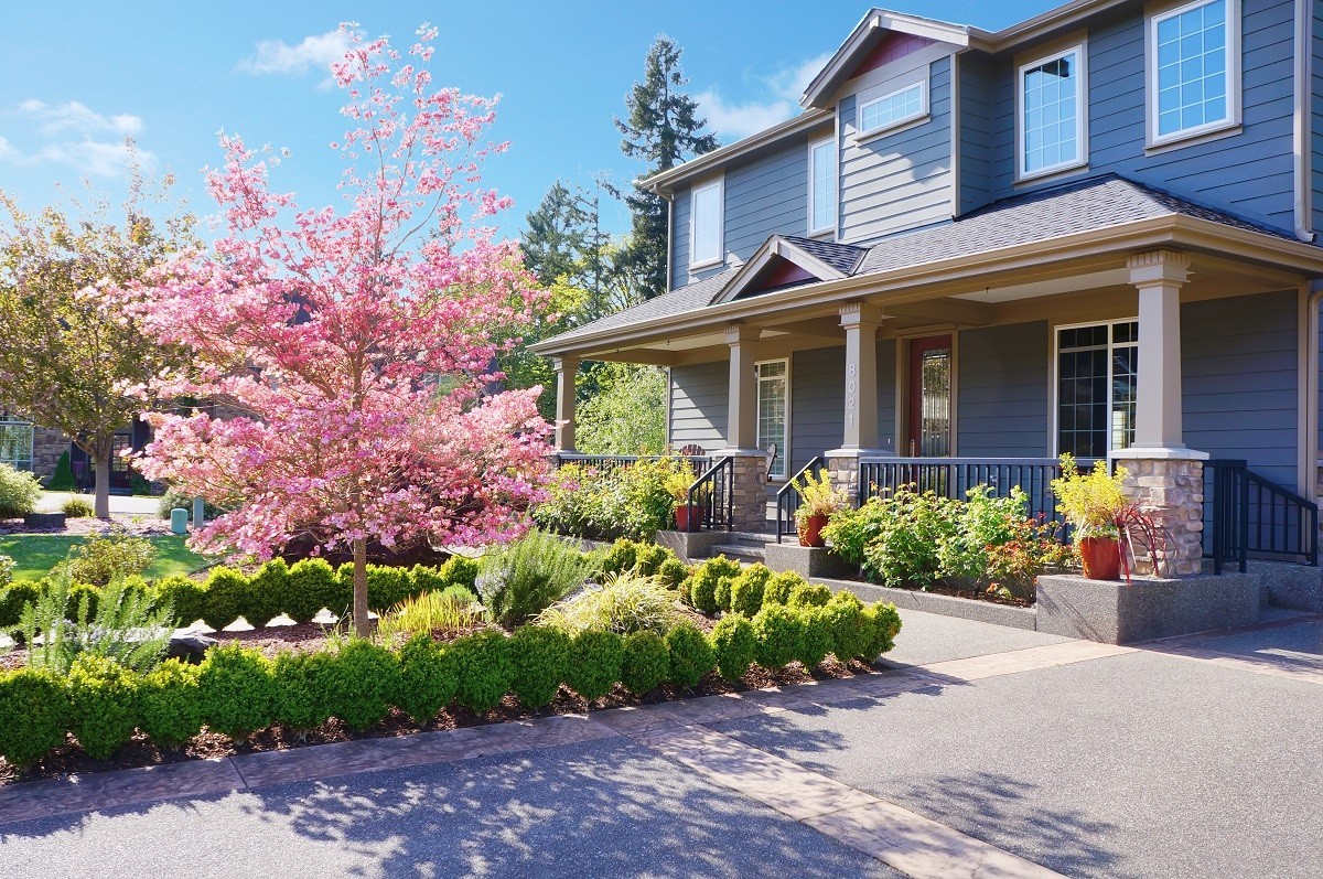 a blue, two-level home with a well-manicured garden in front