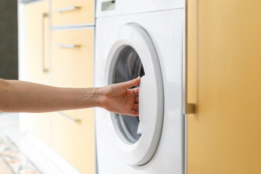 a homeowner pulling a washing machine door - washing machine troubleshooting