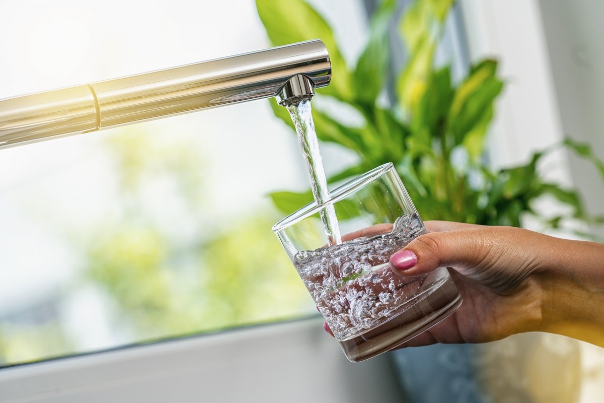a kitchen sink filling up a small glass - PFAS chemicals