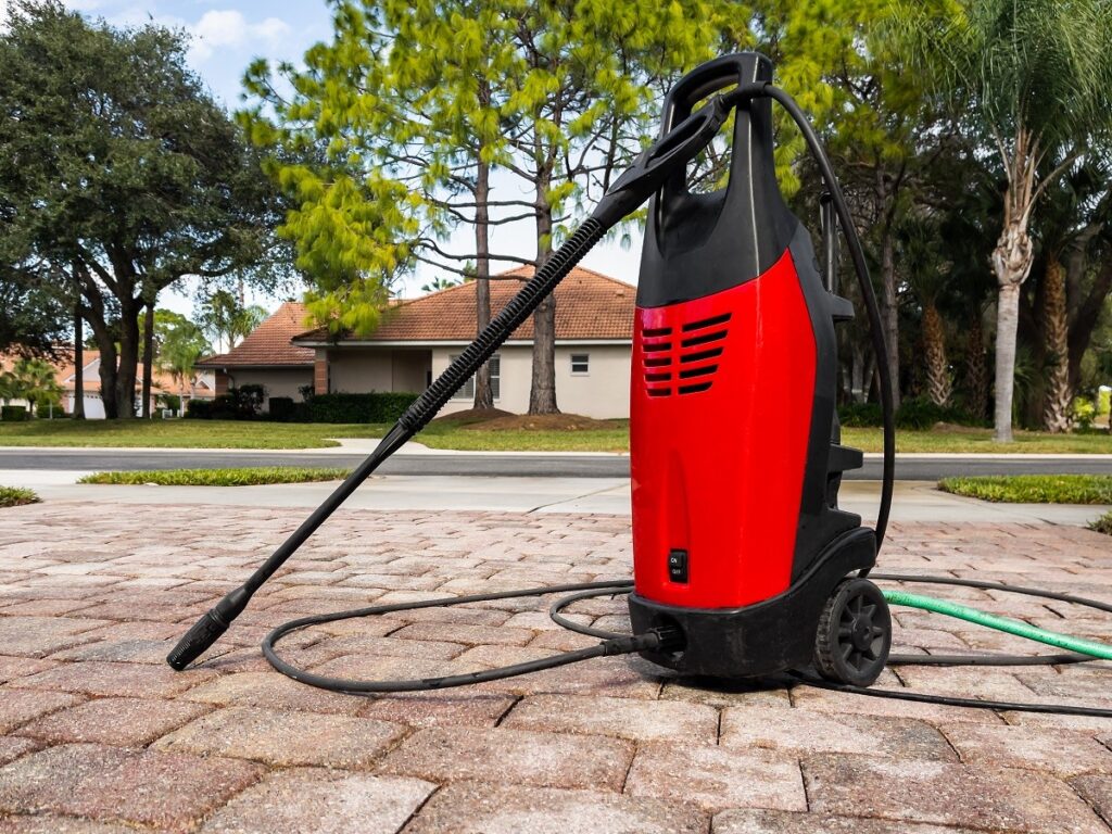 a red electrical power washer on a driveway - how to power wash your home