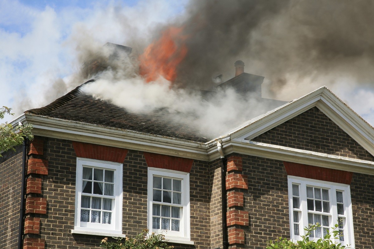 a fire burning through a roof of a home - home fire safety
