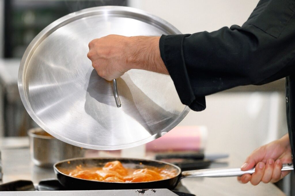oversized pot lid being held over a pan