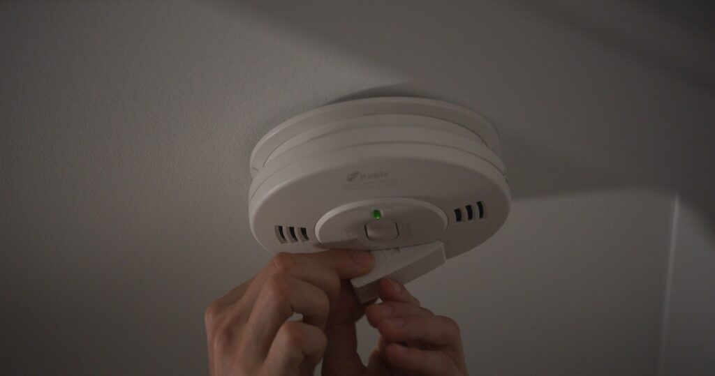 person changing smoke detector batteries