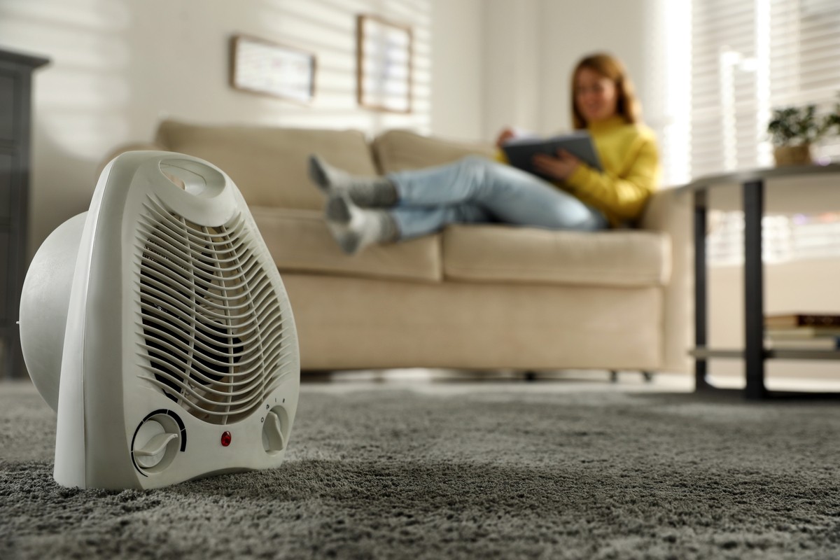 woman sitting on couch enjoying a space heater