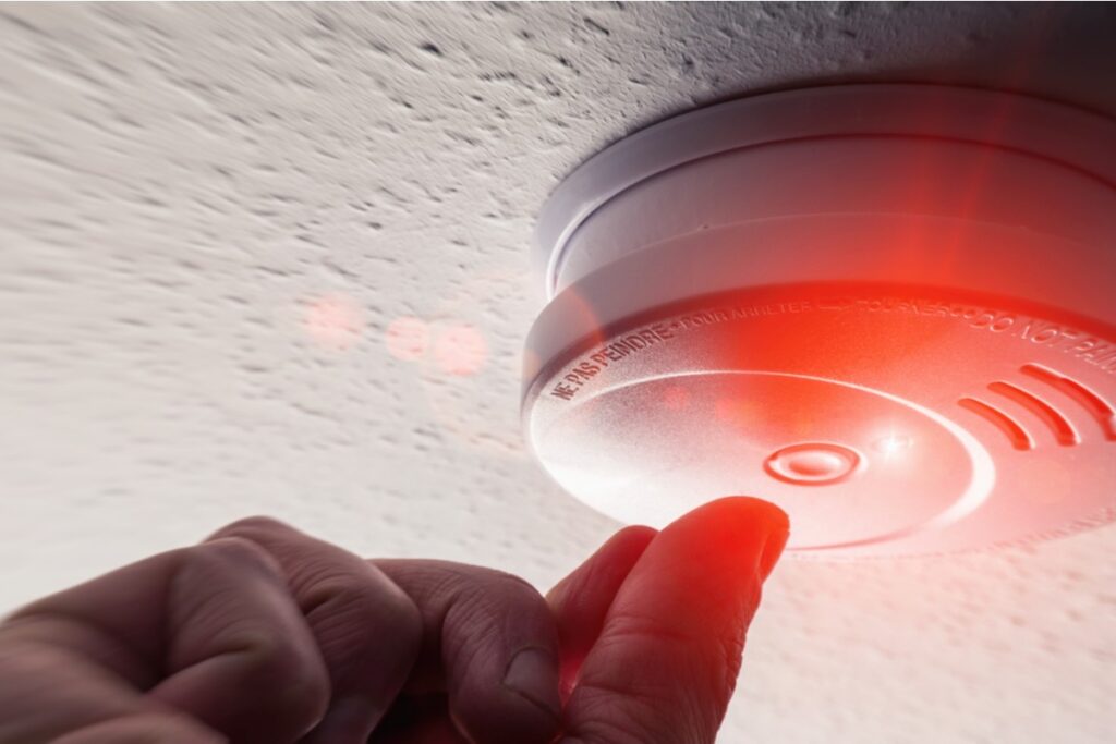 Person pushing the smoke detector test button