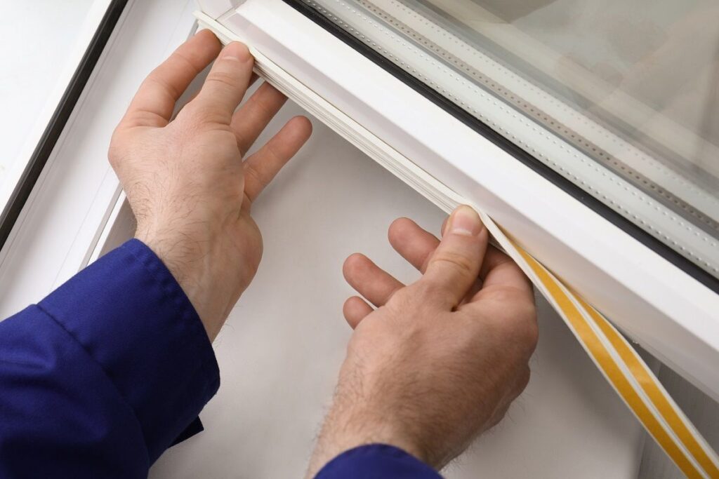 Person adding weather stripping to a window