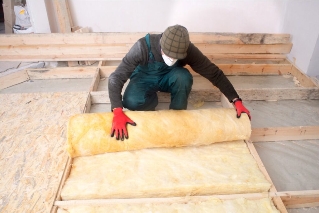 professional rolling out insulation on a floor