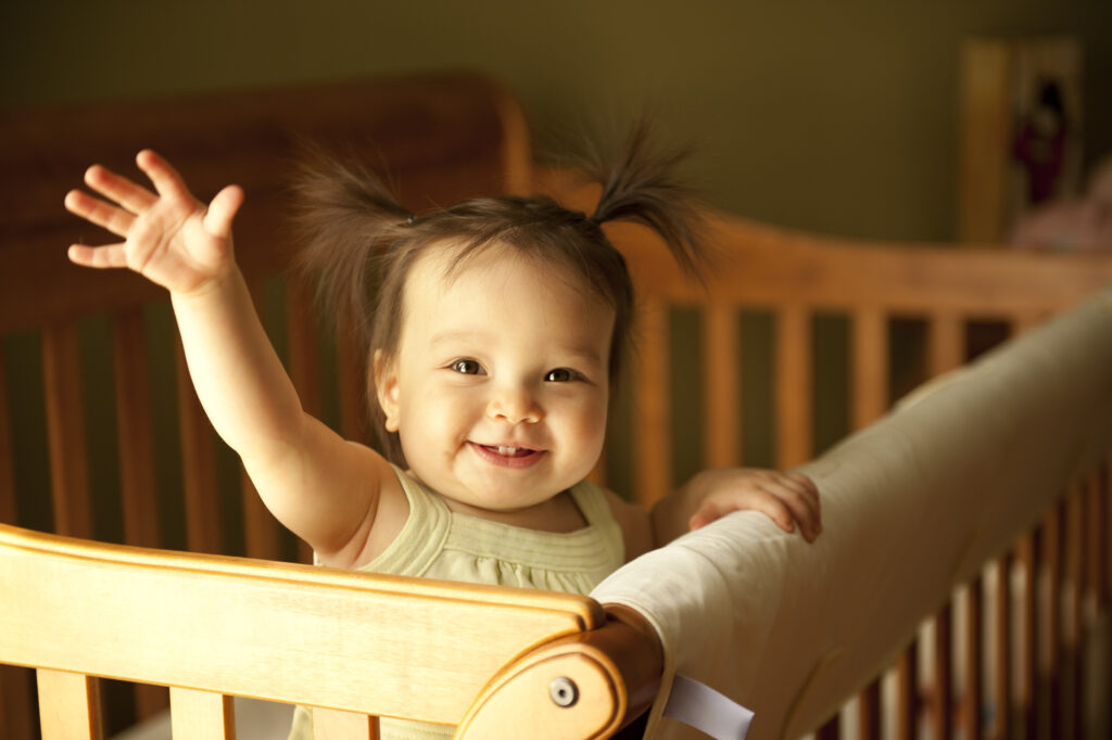 A baby reaching out of a crib