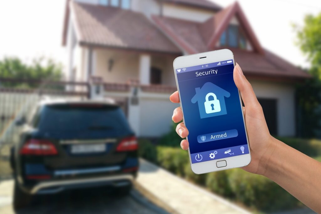 a person holding up a phone with a lock on the screen in front of a home and car